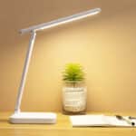 Lampe Rechargeable de Table Pliable sur fond beige posée sur une table avec une plante, et un cahier